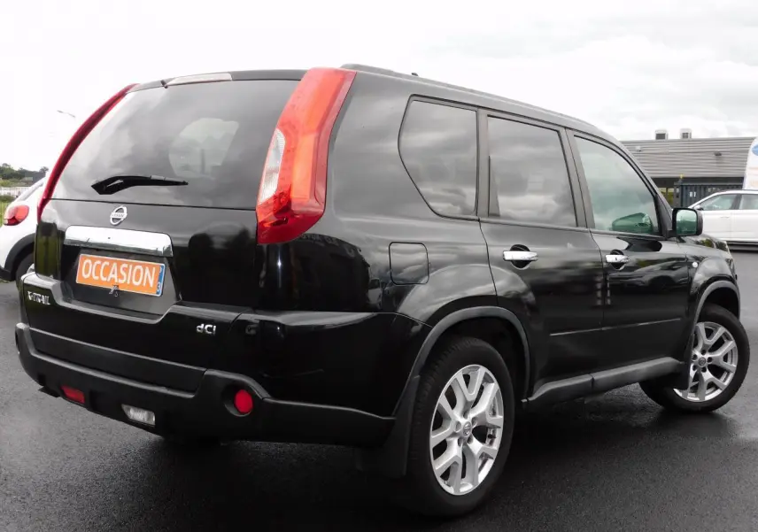 Vue 3/4 arrière droite d'un Nissan X-Trail noir 2011 avec feux arrière verticaux et jantes alliage argentées.