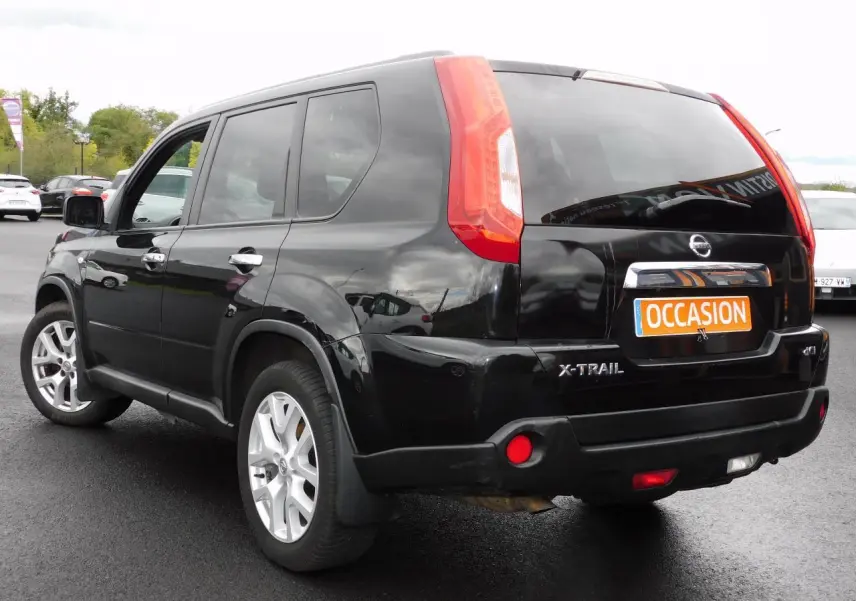 Nissan X-Trail noir vu de trois quarts arrière droit, avec feux arrière verticaux et plaque orange "OCCASION" visible.