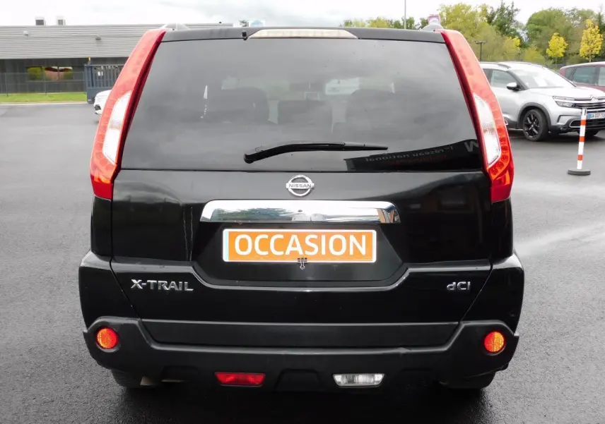 Vue arrière d'un Nissan X-Trail noir avec feux rouges verticaux et plaque "OCCASION" orange visible.
