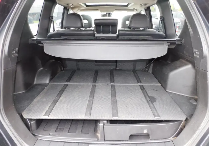 Coffre ouvert du Nissan X-TRAIL noir 2011, montrant le Flexiboard® à deux niveaux avec cache-bagages enrouleur.