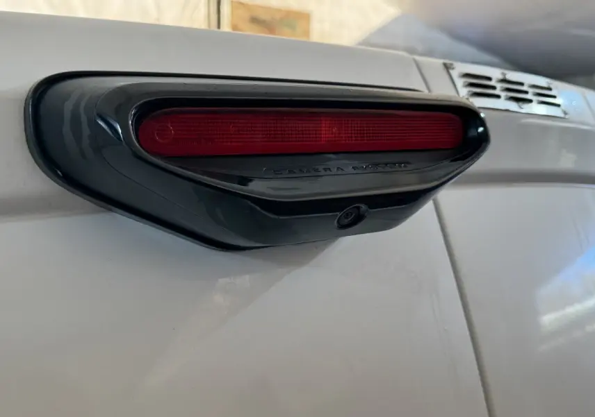 Gros plan sur le feu stop arrière avec caméra intégrée du Citroën Berlingo blanc, vue de côté droit.