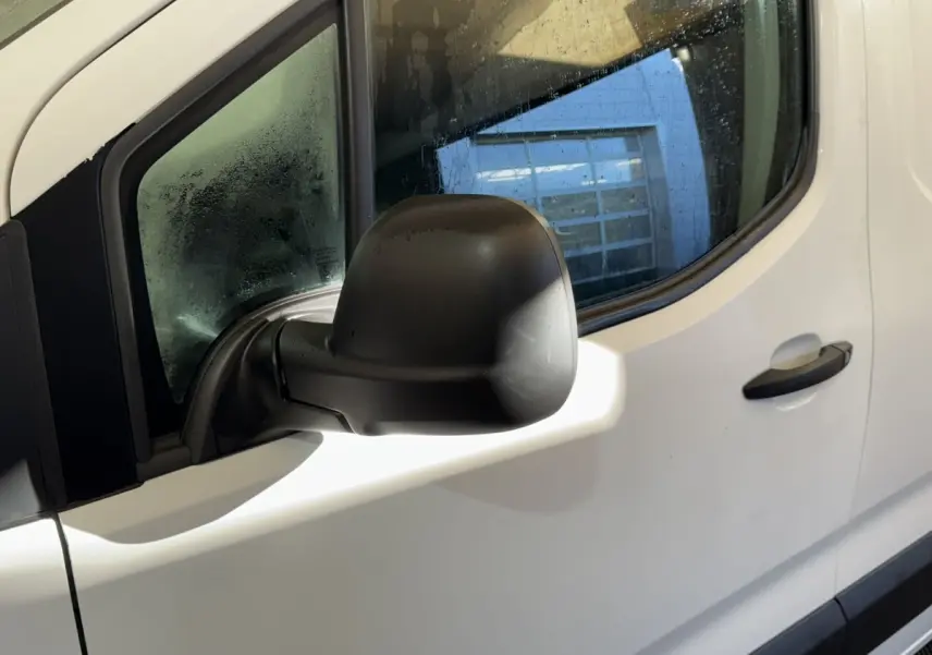 Rétroviseur noir côté conducteur en gros plan sur la porte blanche d'un Citroën Berlingo 2020.