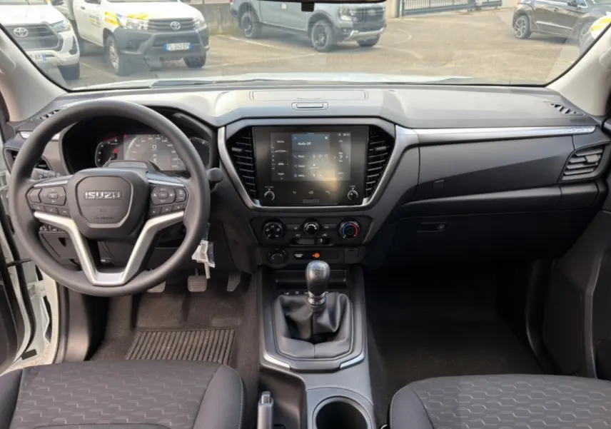 Vue intérieure avant de l'Isuzu D-MAX 2.2 TD 164 Space Evolution avec tableau de bord noir et écran tactile central.