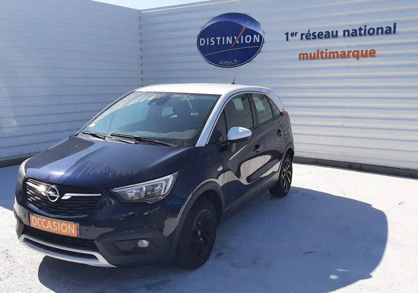 Opel Crossland noir avec toit blanc en 3/4 avant droit, stationné devant un mur blanc avec logo Distinxion.