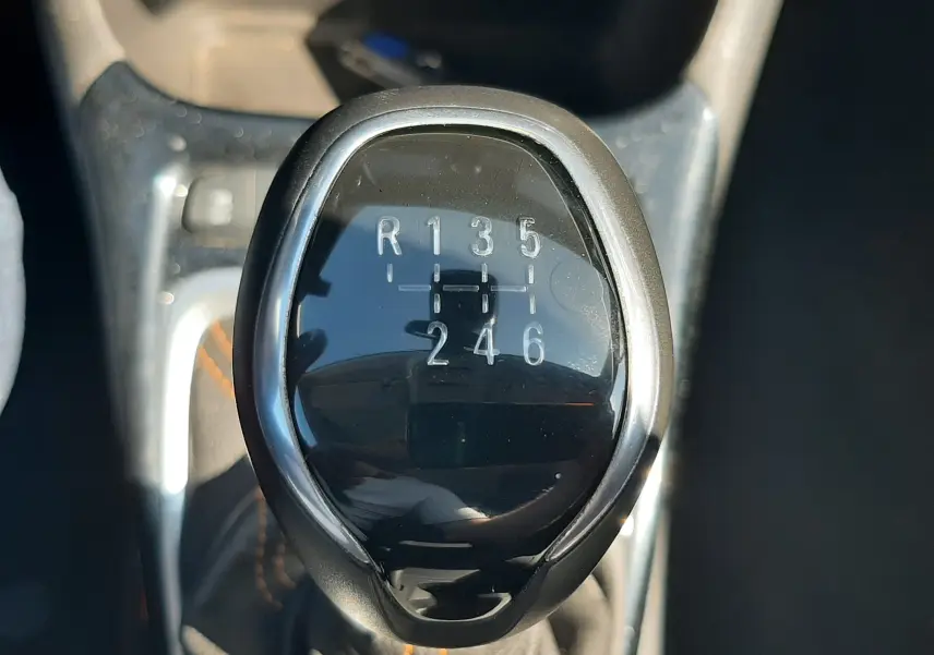 Vue rapprochée de la console centrale avec frein à main manuel et siège tissu gris de l'Opel Crossland noir toit blanc 2019.