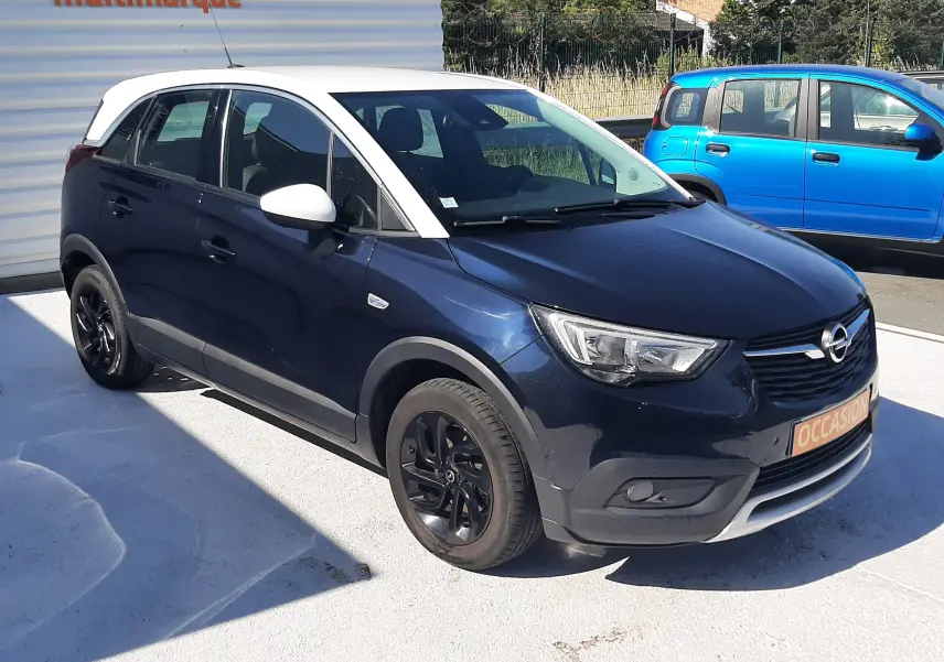 Vue avant d'un Opel Crossland noir avec toit blanc, affichant le prix et des options sur le pare-brise.