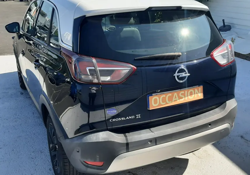 Opel Crossland noir avec toit blanc vu de trois quarts arrière droit, stationné en extérieur au soleil.