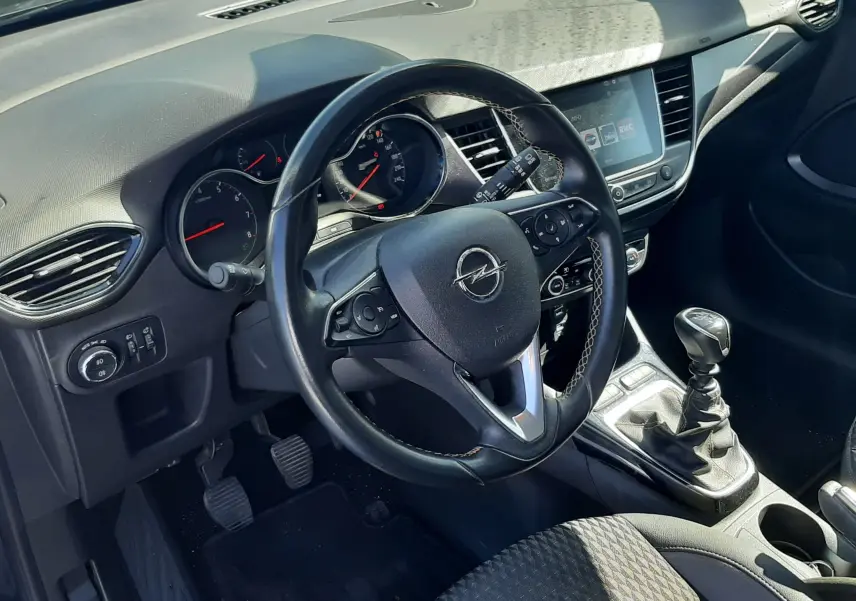 Gros plan sur la roue avant gauche de l'Opel Crossland noir avec jante noire au design moderne et logo Opel central.