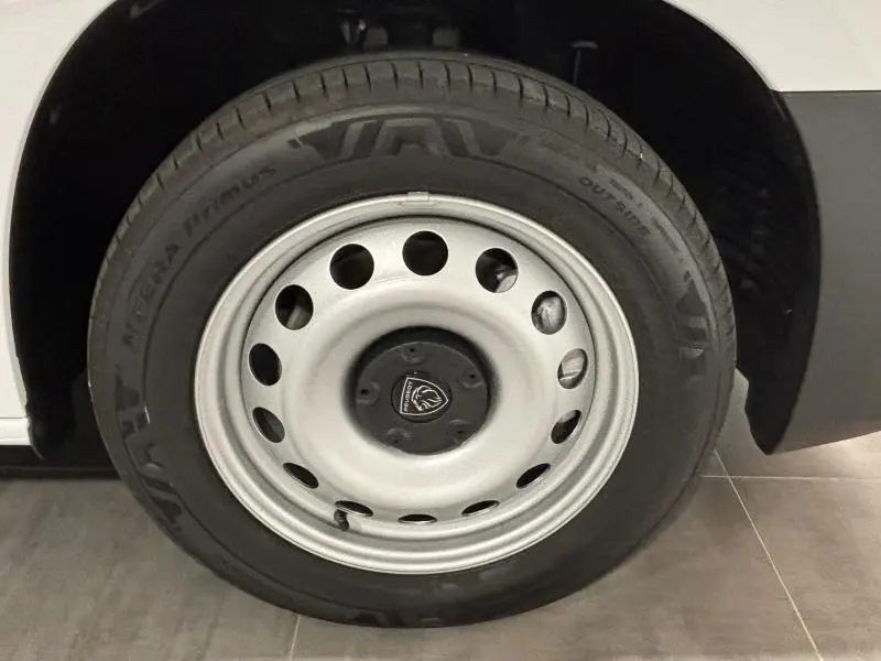 Gros plan sur la roue avant droite du Peugeot Partner XL blanc Icy avec jante acier et logo Peugeot central.