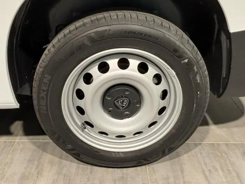 Gros plan sur la roue avant gauche du Peugeot Partner XL blanc Icy avec jante acier et logo Peugeot central.