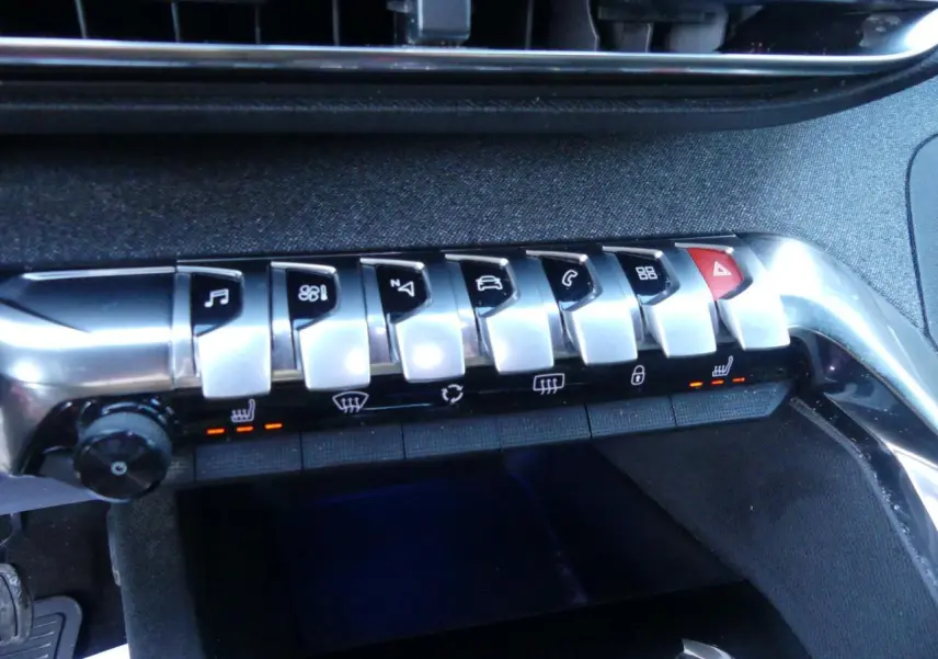 Boutons de commande chromés du tableau de bord du Peugeot 3008 GT Line 2020, avec éclairage orange des sièges chauffants.