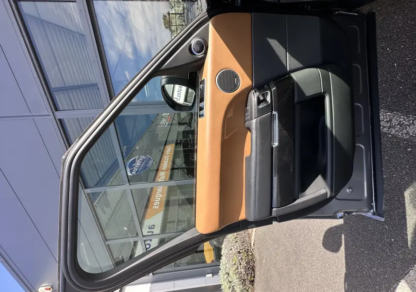 Vue de la porte avant gauche ouverte d'un Range Rover Sport SVR 2020 gris foncé avec intérieur cuir marron et noir.
