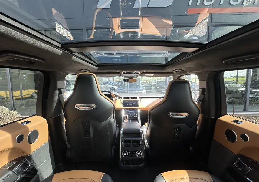 Vue intérieure arrière du Range Rover Sport 2020 gris foncé, avec sièges sport noirs et camel et toit panoramique.