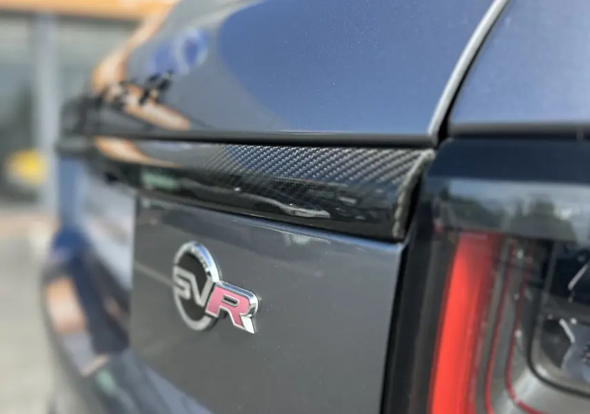 Gros plan sur l'arrière droit gris foncé du Range Rover Sport SVR Carbon Edition, mettant en valeur l'emblème SVR et le feu arrière.