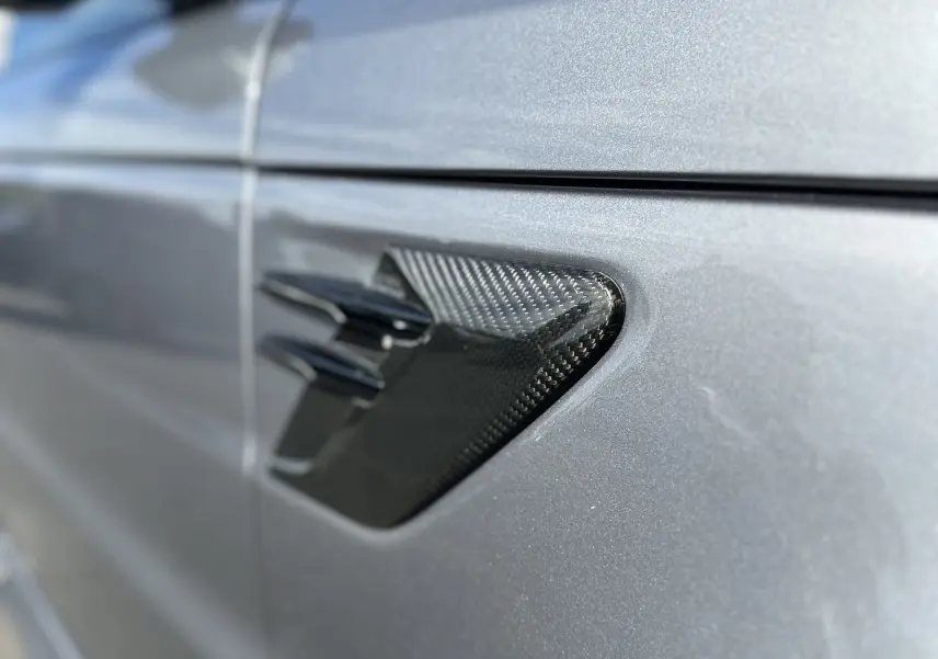 Gros plan sur la prise d'air en carbone côté gauche d'un Range Rover Sport gris foncé 2020 édition SVR Carbon.