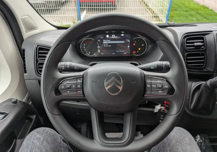Vue intérieure centrée sur le volant et le combiné numérique du Citroën Jumper blanc 2025, avec clé visible.