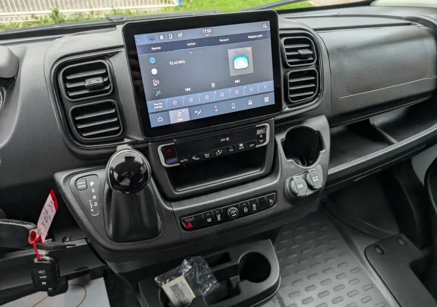 Vue rapprochée du tableau de bord noir du Citroën Jumper 2025, avec écran tactile 10 pouces et levier de boîte automatique.