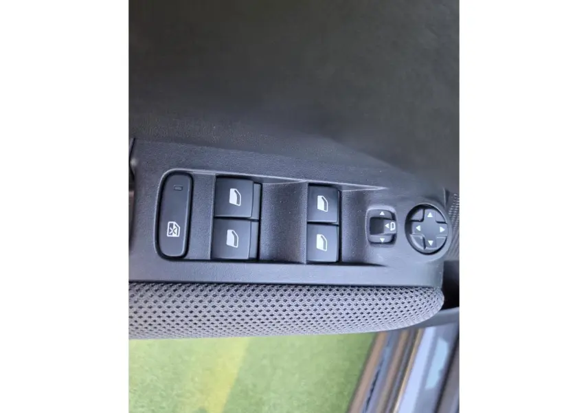 Gros plan sur les commandes des vitres électriques et réglages des rétroviseurs côté conducteur d'une Citroën C3 Aircross gris platinium.