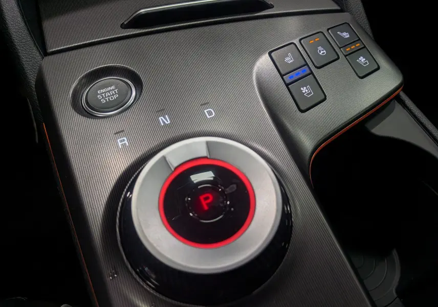 Gros plan sur la console centrale du Kia Sportage 2025 avec sélecteur rotatif de boîte auto et commandes de sièges chauffants.