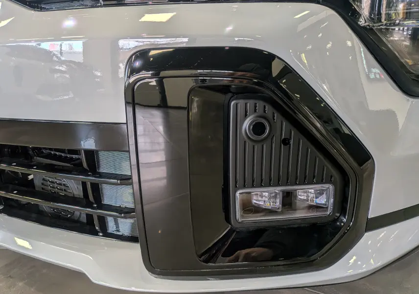 Gros plan sur le phare avant droit noir et gris céramique du Kia Sportage 2025 GT Line hybride.