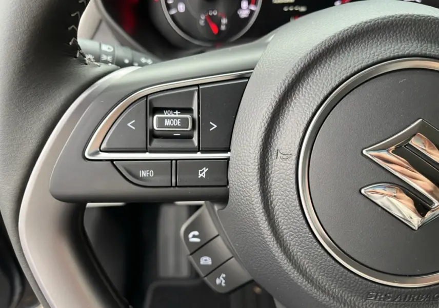 Gros plan sur le volant cuir multifonctions gris de la Suzuki Swift 2025 avec commandes audio et téléphone intégrées.