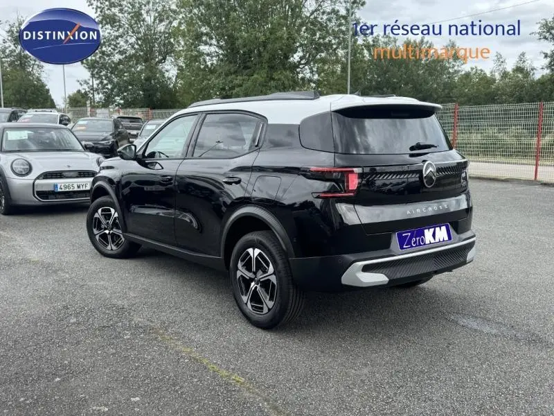 Vue 3/4 arrière droite d'un Citroën C3 Aircross noir Perla Nera avec toit blanc et jantes alu distinctives.