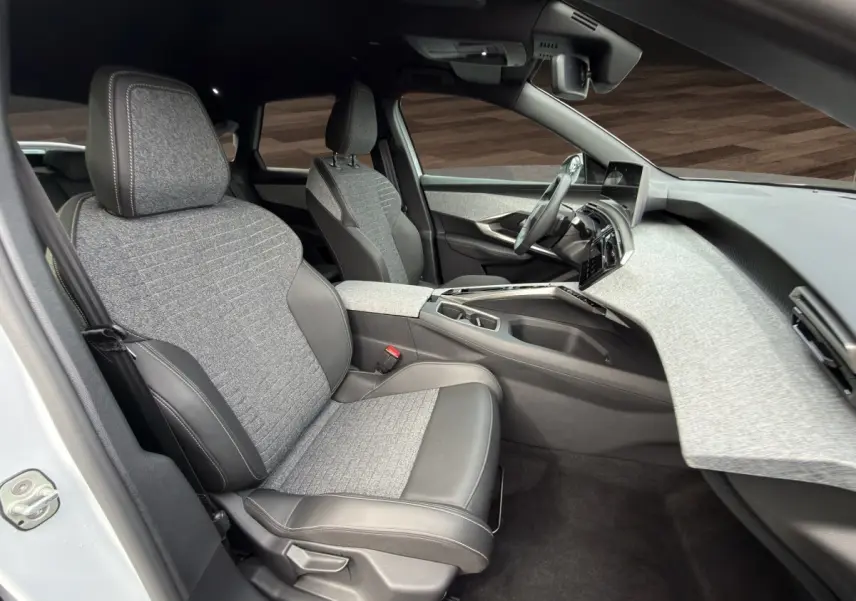Intérieur avant droit du Peugeot 3008 blanc 2025, sièges tissu et cuir gris, tableau de bord clair moderne.