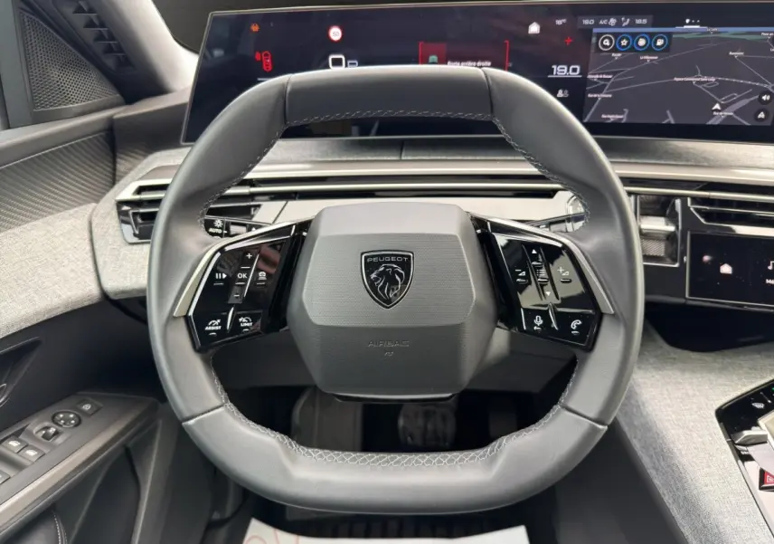 Vue rapprochée du volant cuir multifonctions du Peugeot 3008 blanc 2025 avec tableau de bord numérique panoramique.