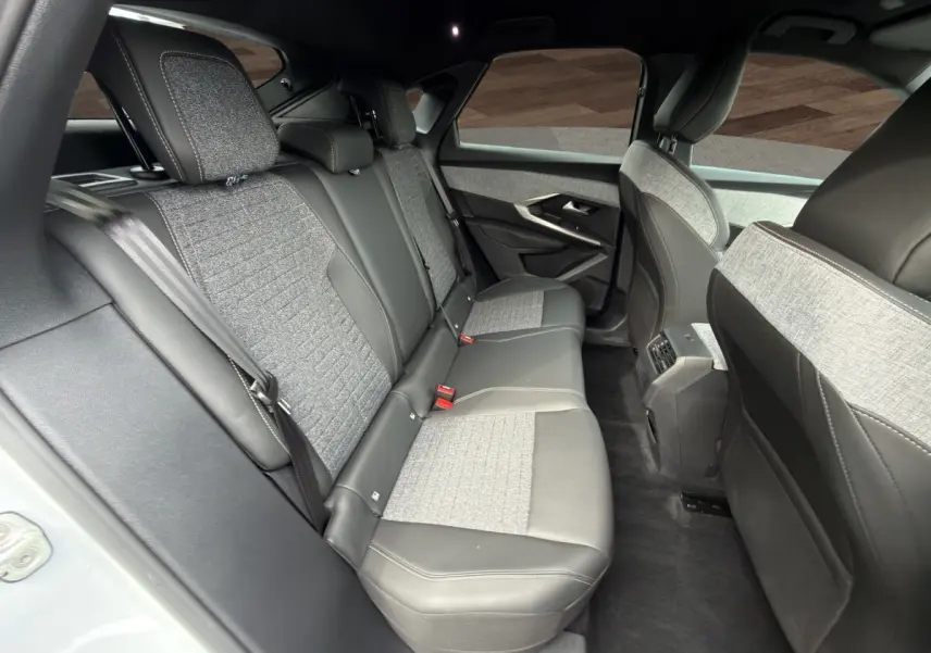 Vue intérieure arrière du Peugeot 3008 2025, sièges bi-matière gris clair et cuir noir avec ceinture de sécurité visible.
