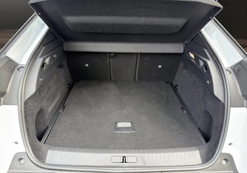 Coffre ouvert vu de l'arrière d'un Peugeot 3008 blanc, espace de chargement propre et spacieux avec cache-bagages relevé.