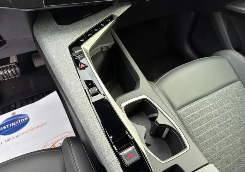 Vue rapprochée de la console centrale grise et noire du Peugeot 3008 blanc, avec porte-gobelets et commandes tactiles.
