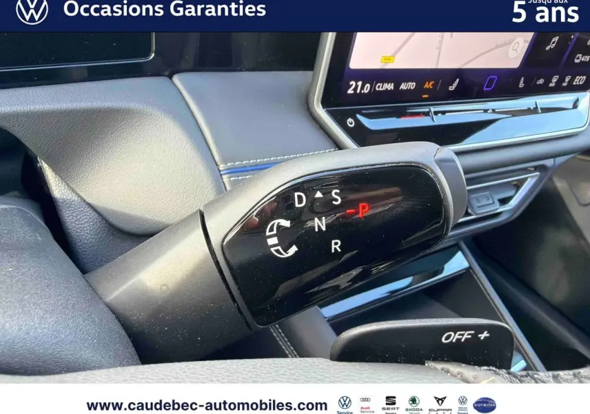 Gros plan sur la commande de boîte manuelle noire dans l’habitacle du Volkswagen Tiguan argent Dolomite, avec écran tactile en arrière-plan.