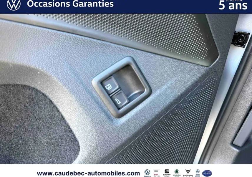 Gros plan sur la commande d'ouverture du hayon et du bouchon de carburant sur la porte intérieure d'un Volkswagen Tiguan argent Dolomite.