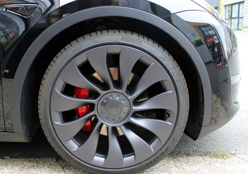 Gros plan sur la roue avant droite noire métallisée d'une Tesla Model Y 2024 avec étrier de frein rouge visible.