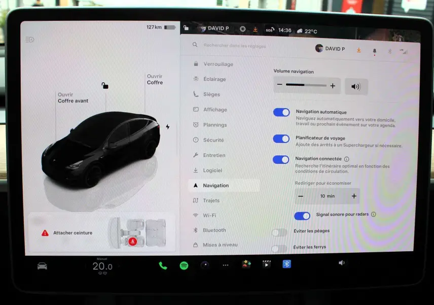 Vue de profil gauche stylisée d'une Tesla Model Y noire métal affichée sur l'écran tactile central.