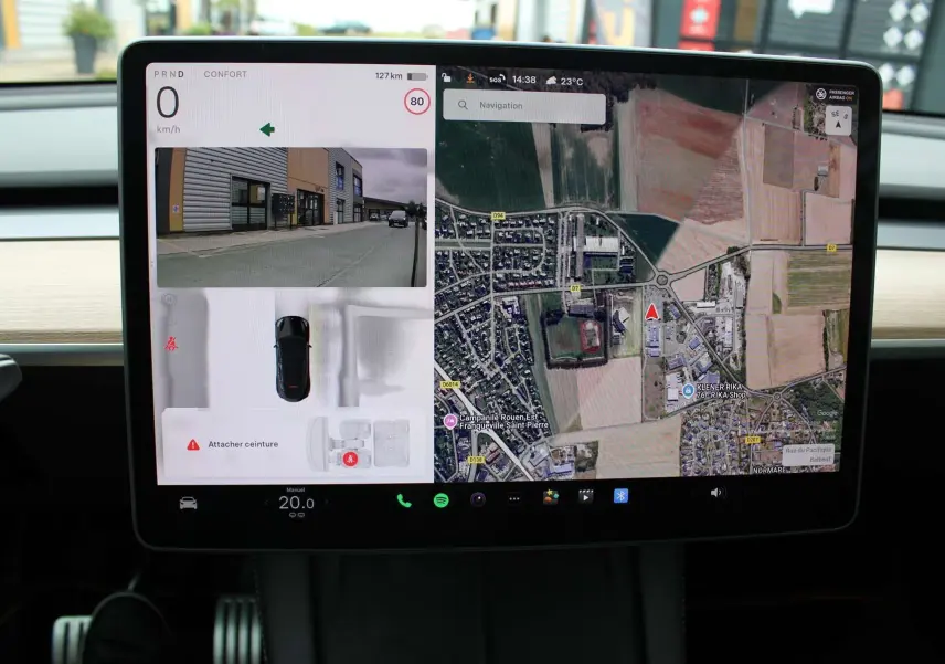 Écran tactile central de la Tesla Model Y Performance 2024 montrant navigation et caméra de recul en intérieur noir.