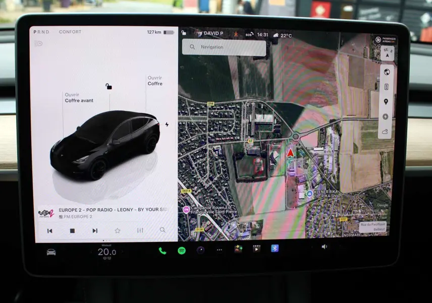 Écran tactile central affichant la Tesla Model Y noire métal en vue 3/4 arrière avec carte GPS et options ouvertes.