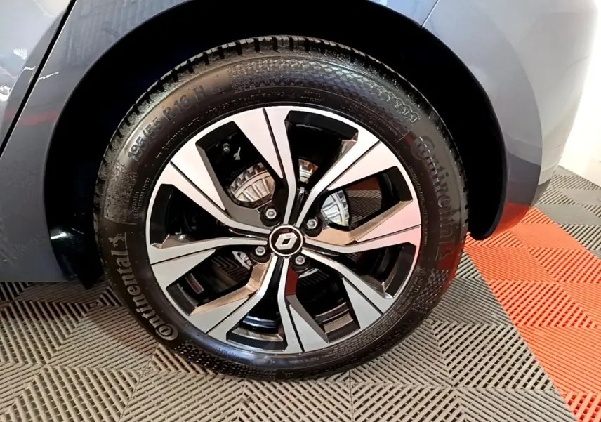 Gros plan sur la roue avant droite gris foncé d’une Renault Clio Evolution SCe 65 avec jante alliage bicolore.