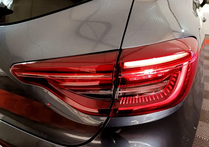 Gros plan sur le feu arrière droit rouge d'une Renault Clio Evolution gris foncé, vue de l'arrière côté droit.