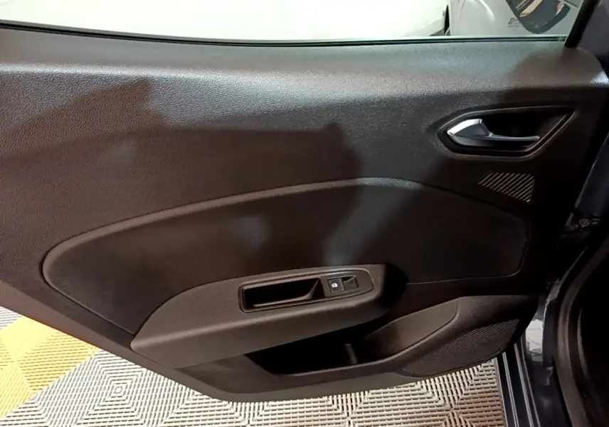 Gros plan sur la porte intérieure côté arrière droit de la Renault Clio gris foncé, avec poignée et commande de vitre.