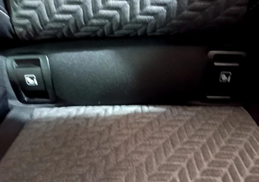 Gros plan sur la banquette arrière grise à motif chevrons de la Renault Clio Evolution SCe 65, avec boutons de rabattement.