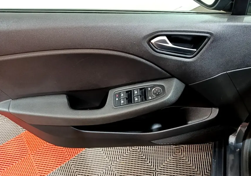 Vue intérieure côté gauche de la porte conducteur d'une Renault Clio gris foncé avec commandes de vitres et poignée métallique.