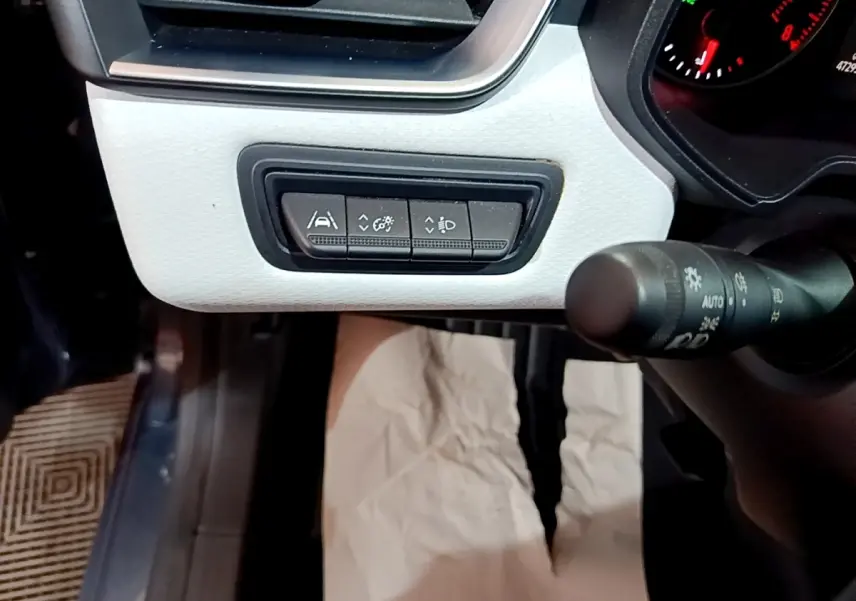 Gros plan sur les commandes d'aide à la conduite et réglages lumineux du tableau de bord blanc de la Renault Clio gris foncé.