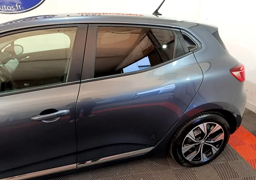 Vue latérale droite d'une Renault Clio gris foncé 2022, mettant en valeur les vitres teintées et les jantes modernes.