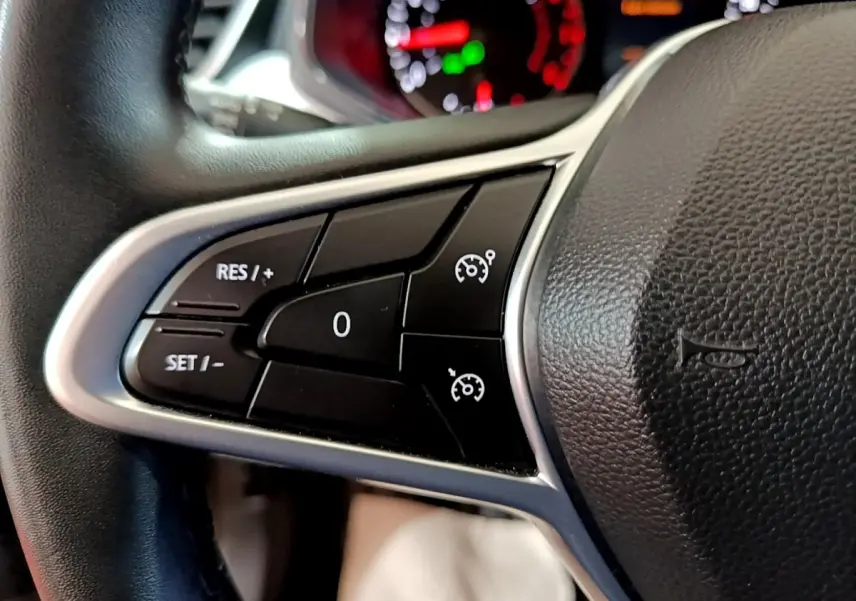 Gros plan sur les commandes de régulateur de vitesse au volant cuir noir de la Renault Clio gris foncé 2022.