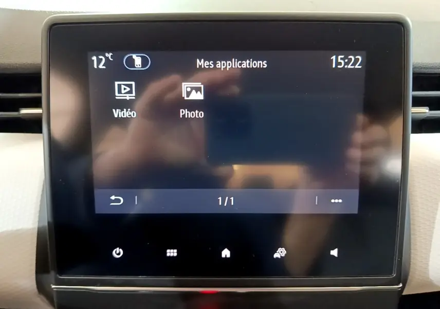 Écran tactile central de la Renault Clio Evolution gris foncé, affichant les applications vidéo et photo, vue de face.