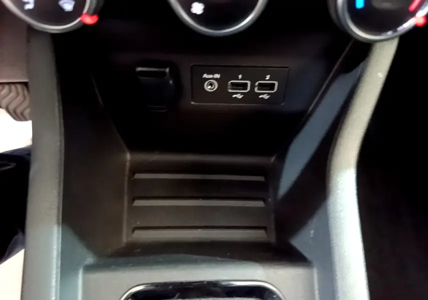 Gros plan sur la console centrale noire de la Renault Clio Evolution SCe 65, avec ports USB et prise auxiliaire visibles.