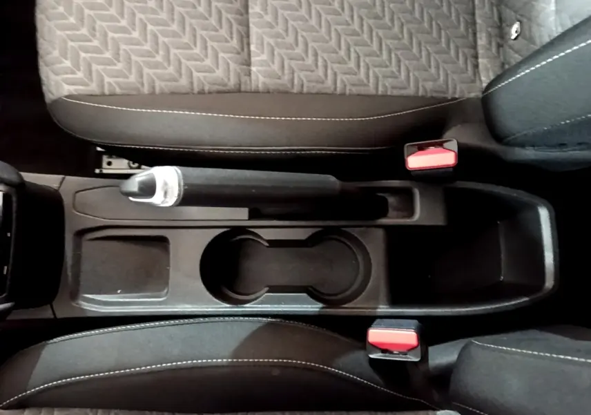 Vue plongeante sur la console centrale noire de la Renault Clio gris foncé avec frein à main manuel et porte-gobelets.