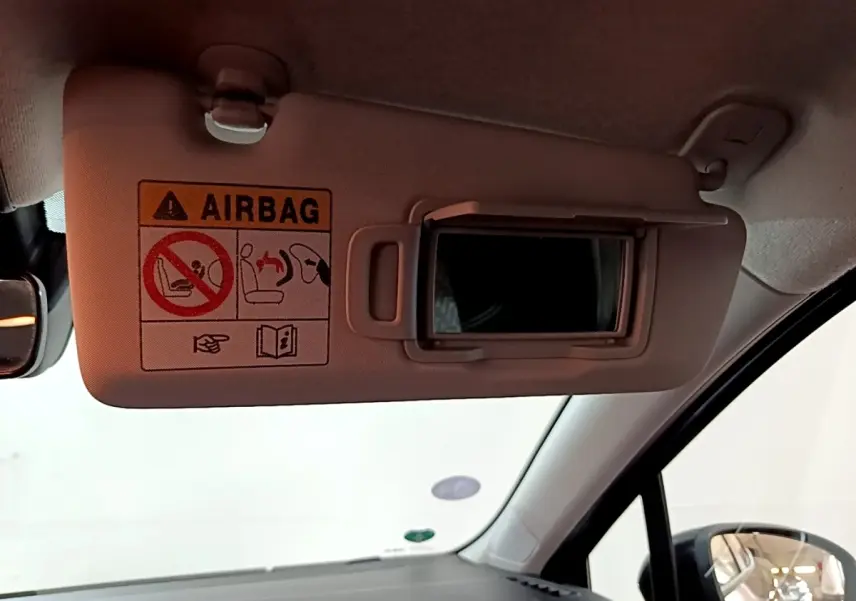 Détail intérieur du pare-soleil côté conducteur avec miroir et avertissement airbag dans une Renault Clio gris foncé.