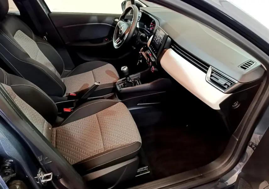 Intérieur avant droit de la Renault Clio gris foncé 2022, montrant sièges tissu bicolore et tableau de bord avec écran tactile.